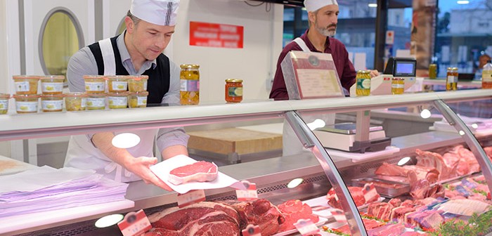 butcher preparing meat behind counter